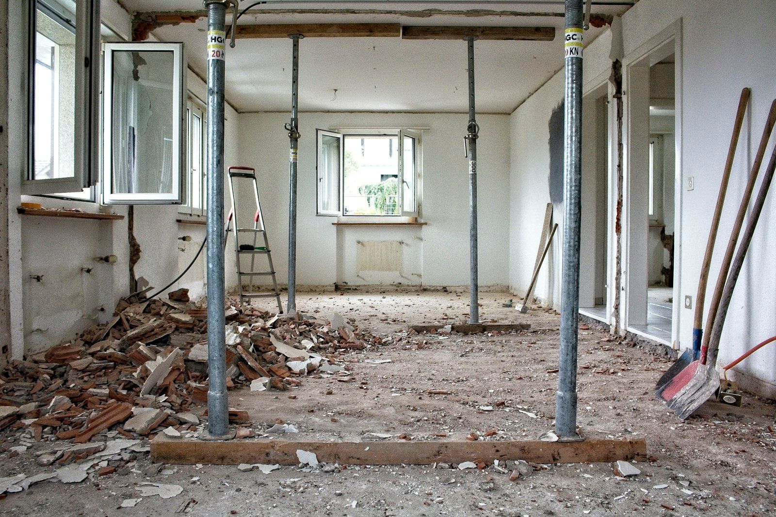 Stanza in ristrutturazione con puntelli metallici, macerie e attrezzi sul pavimento